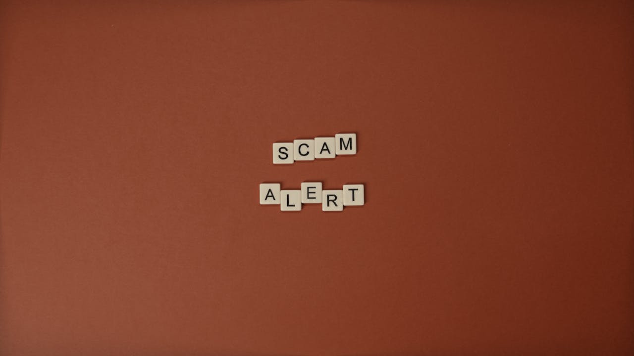 Services Scrabble tiles spelling Scam Alert on a brown surface indicating caution.