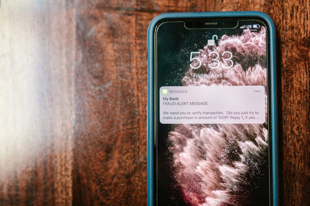 Services Close-up of a smartphone displaying a fraud alert notification on a wooden surface.